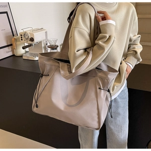 Détail du grand sac cabas en nylon avec cordons de serrage latéraux et larges bandoulières
