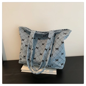 Close-up of light blue corduroy shoulder bag with black argyle and bow pattern details