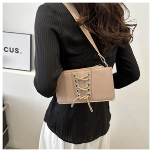 Détail du sac à bandoulière en similicuir beige avec laçage tendance et œillets métalliques