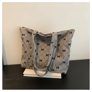 Detailed macro view of gray corduroy tote bag with black diamond pattern and bow accents