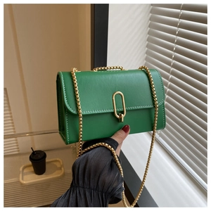 Détail du petit sac carré vert avec surpiqûres blanches et fermoir en métal doré