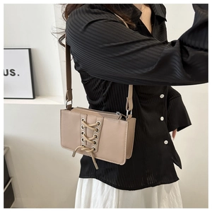 Détail du sac à bandoulière en cuir verni avec lacets croisés et œillets métalliques