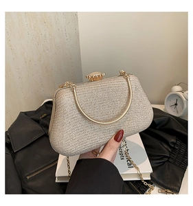 Close-up of champagne gold glitter evening bag with crown clasp and metal chain handle