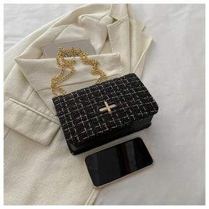 Detail of black tweed crossbody bag with gold chain strap and metal swivel lock