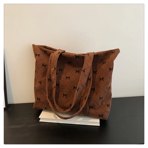Macro detail of brown corduroy tote bag with black bow print and classic quilted pattern
