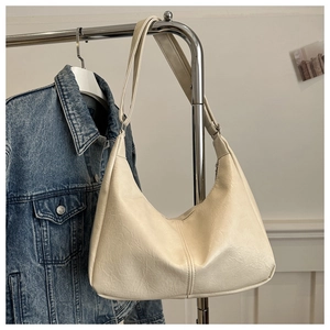 Close-up of off-white leather tote bag with grainy texture hanging on a silver rack