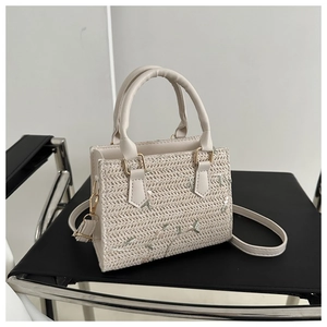 Detailed texture of cream woven straw bag with floral embroidery on a black chair
