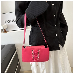 Détail du sac à bandoulière rose vif avec lacets croisés et œillets argentés