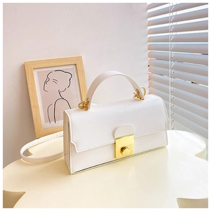 Detailed view of the white leather handbag with a prominent golden metal buckle lock