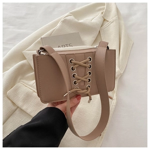 Détail du sac à bandoulière beige en simili cuir avec un design croisé à lacets à l'avant