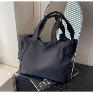 Close-up of large black nylon tote bag with drawstring side details on a storage cabinet
