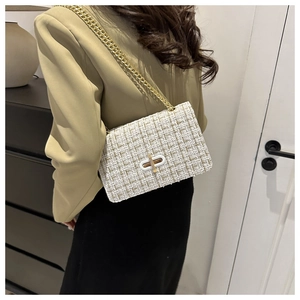 Close-up of white tweed crossbody bag with gold metallic threads and a golden chain strap