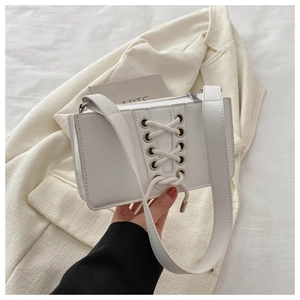 Détail du sac bandoulière en similicuir blanc avec un design à lacets et œillets chic