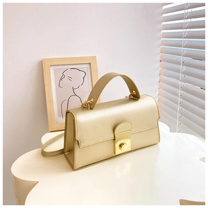 Detailed view of the gold crossbody bag featuring a metal lock and textured PU leather