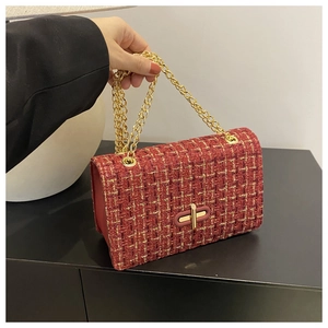 Close-up of red tweed crossbody bag featuring a golden chain strap and sleek metal lock