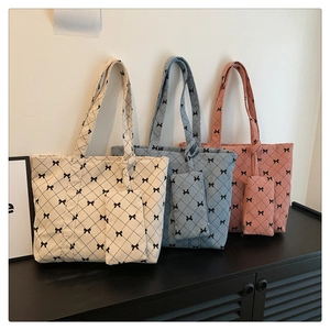 Detailed close-up of corduroy tote bags with bow patterns in cream, blue, and pink colors