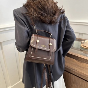 Dunkelbraune College-Umhängetasche im Vintage-Stil, getragen als Crossbody am Modell