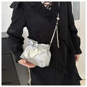 Detail of silver pleated cloud bag featuring a slim metal chain and decorative sphere charm
