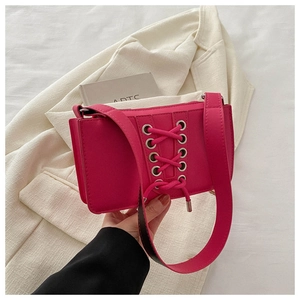Détail du sac bandoulière en cuir verni fuchsia avec œillets argentés et lacets croisés