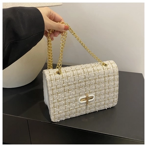 Detail of white tweed crossbody bag showing the golden metal turn-lock and woven texture