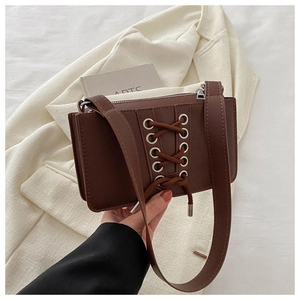 Vue détaillée du sac bandoulière en cuir verni marron avec laçage croisé décoratif
