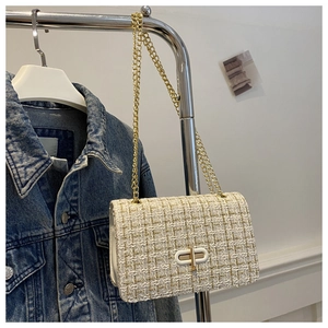 Close-up of white tweed crossbody bag with golden chain and metallic turn-lock closure
