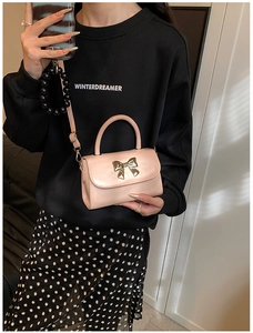 Detail of pink patent leather mini bag with gold bow hardware and crossbody strap