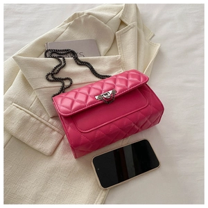 Detail of rose pink quilted crossbody bag with silver twist lock on a business suit background