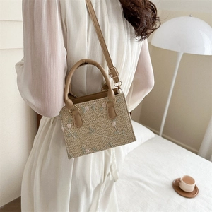 Women's straw crossbody bag with floral embroidery and top handle for beach outings