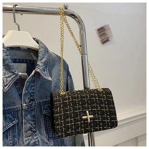 Detail of classic black tweed crossbody bag with gold chain and metal lock closure