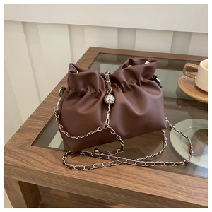 Detail of dark brown leather cloud bag with elegant pleated design and silver chain strap