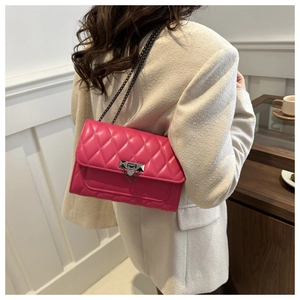 Detail of rose pink quilted crossbody bag featuring metal V-lock and chain strap