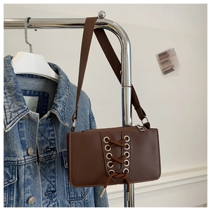 Vue détaillée du sac à bandoulière en cuir verni marron avec lacets et œillets