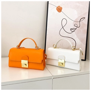 Detail of vibrant orange and white minimalist handbags with golden metal press locks