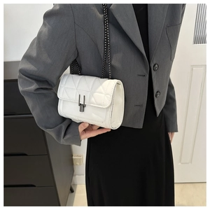 Detail of white quilted leather crossbody bag with chain strap and metal clasp on model