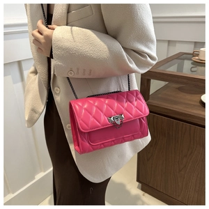 Close-up of rose red quilted chain bag with shield buckle worn on model shoulder
