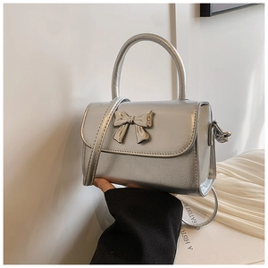 Detail of silver metallic handbag with glossy bow hardware and chic top handle texture