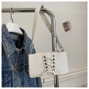 Détail du sac à bandoulière blanc rectangulaire avec laçage et œillets métalliques
