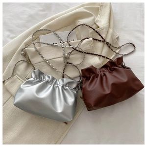 Detail of silver and brown pleated cloud bags with metal chains and spherical charms