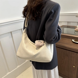 Minimalist beige hobo bag for women featuring a cute pink teddy bear charm and wide strap