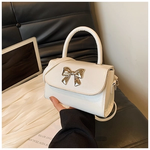 Detail of white glossy mini handbag featuring a silver mirror metal bow and handle