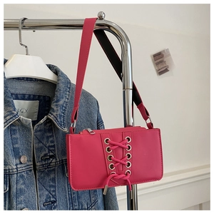 Détail du sac baguette en cuir verni rose avec lacets tendance et œillets métalliques