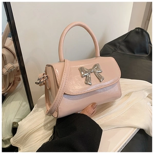 Close-up of pink patent leather handbag with a polished silver metal bow detail