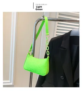 Hellgrüne Tasche mit Krokoprägung und Kettenriemen an einem Kleiderständer hängend