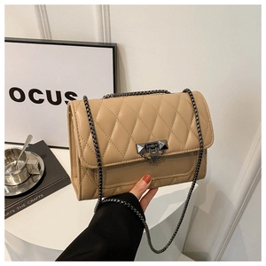 Detailed side view of beige quilted crossbody bag with metal chain and modern clasp