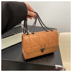 Detail of caramel leather crossbody bag featuring quilted patterns and dark metal chain strap