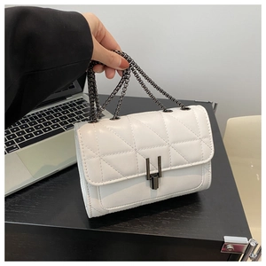Macro shot of white quilted leather bag with dark metallic chain and vertical twist lock