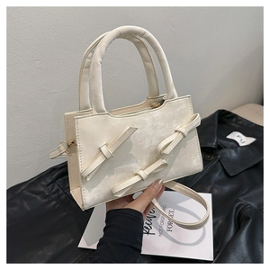 Detail of cream white handbag with three 3D bows and vintage faux leather texture