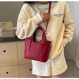 Détail du sac cabas en cuir rouge texturé avec ferrures dorées et bandoulière réglable