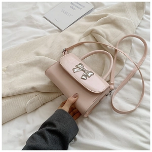 Detail of pink glossy handbag with silver bow metal buckle and thin shoulder strap